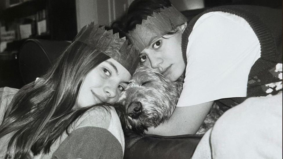 dau ferch yn rhoi mwythau i gi