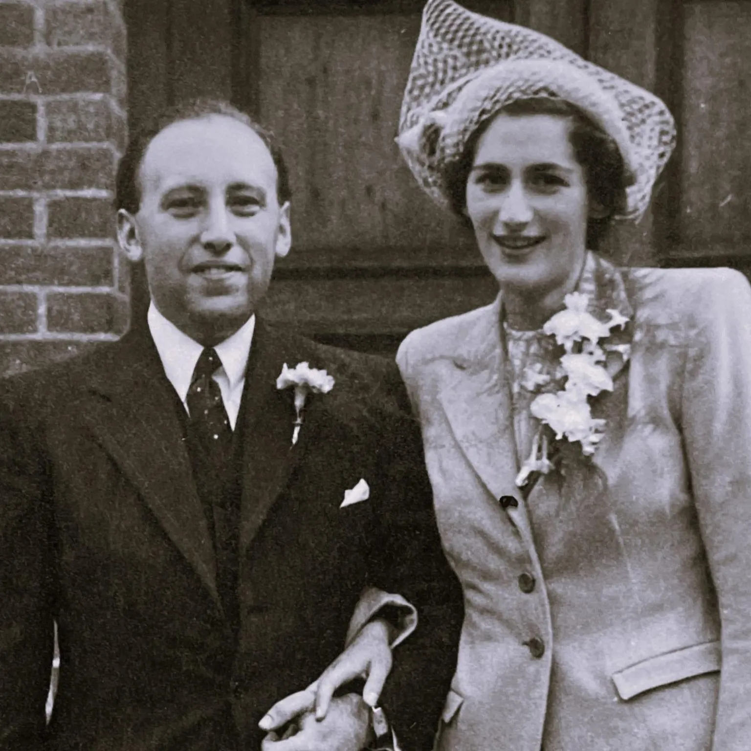 Moritz Family Photo A black and white image of Sir Michael's parents. His dad is on the left and in a black suit with a white tie. His mother, on the right, wears a light suit and has a veil on her head. Both are looking at the camera.