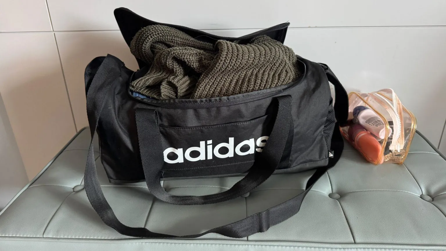 Laura Poole Photo of black Adidas gym bag which is open showing clothes packed inside.
