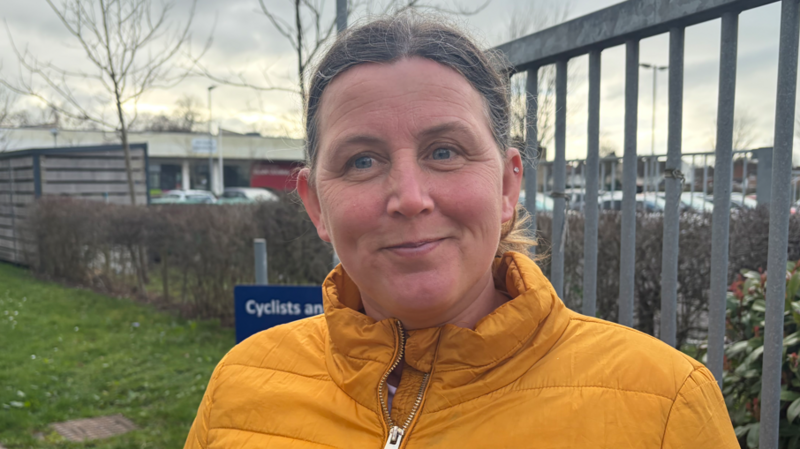 Menyw menyw cot felen yn sefyll ar bwys gat ysgol