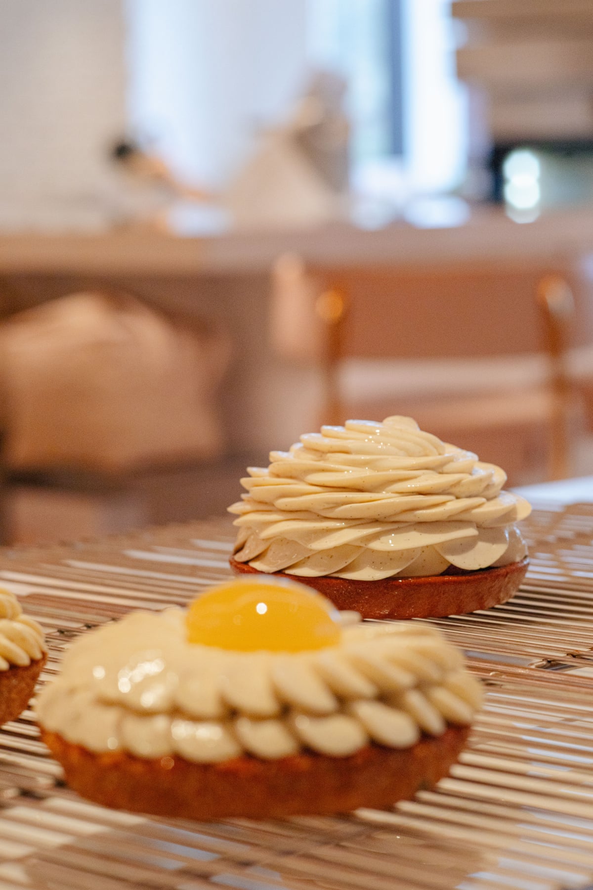 Two frosted pastries, styled to look like flowers, on a wire rack