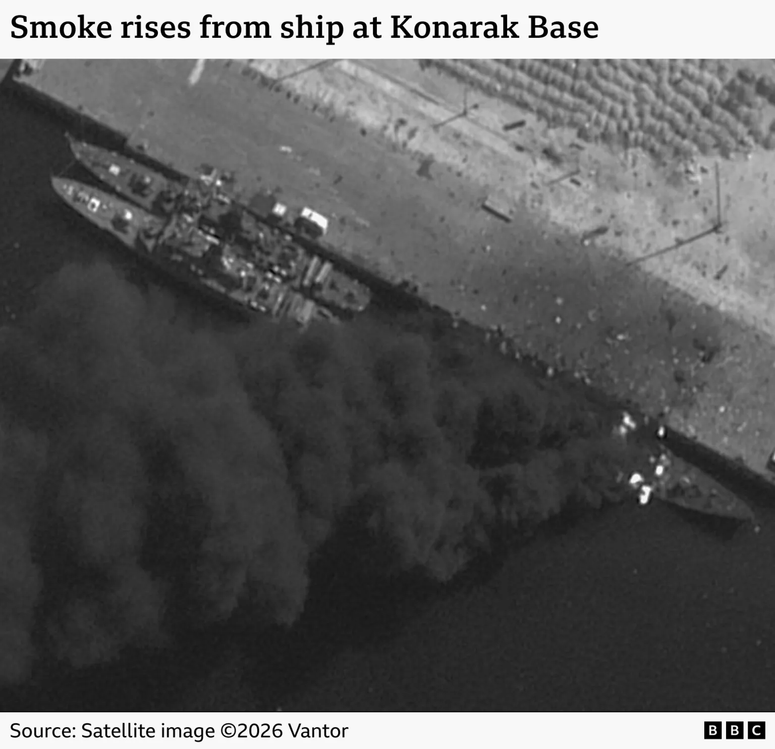 Three ships are seen docked at an Iranian port in a satellite image. Smoke can be seen billowing from one of the ships. The image is captioned 