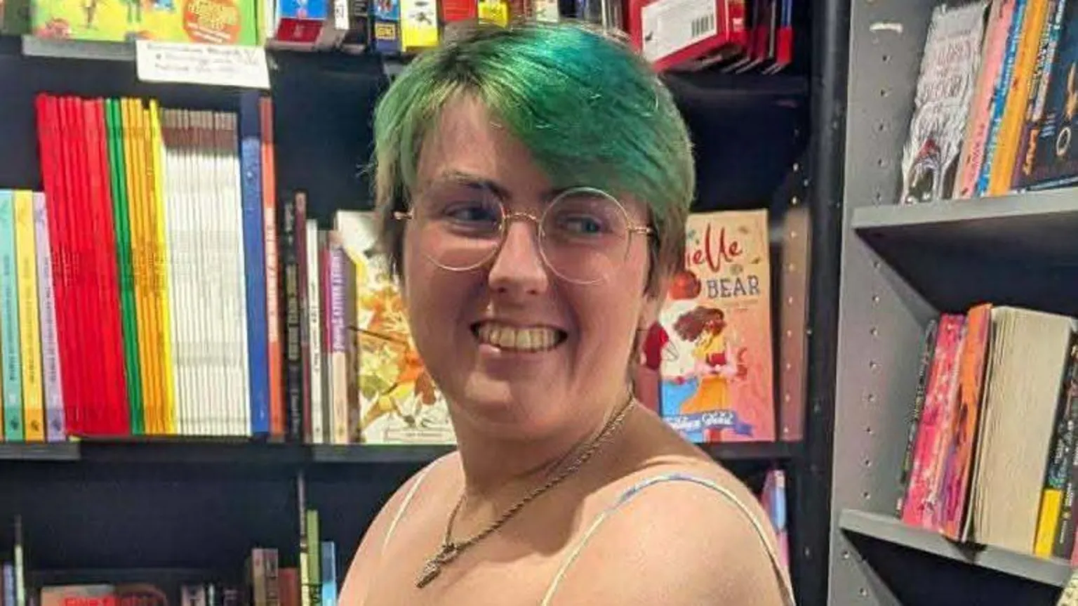 Erin Curran Erin in front of bookshelves. She has green/blue hair
