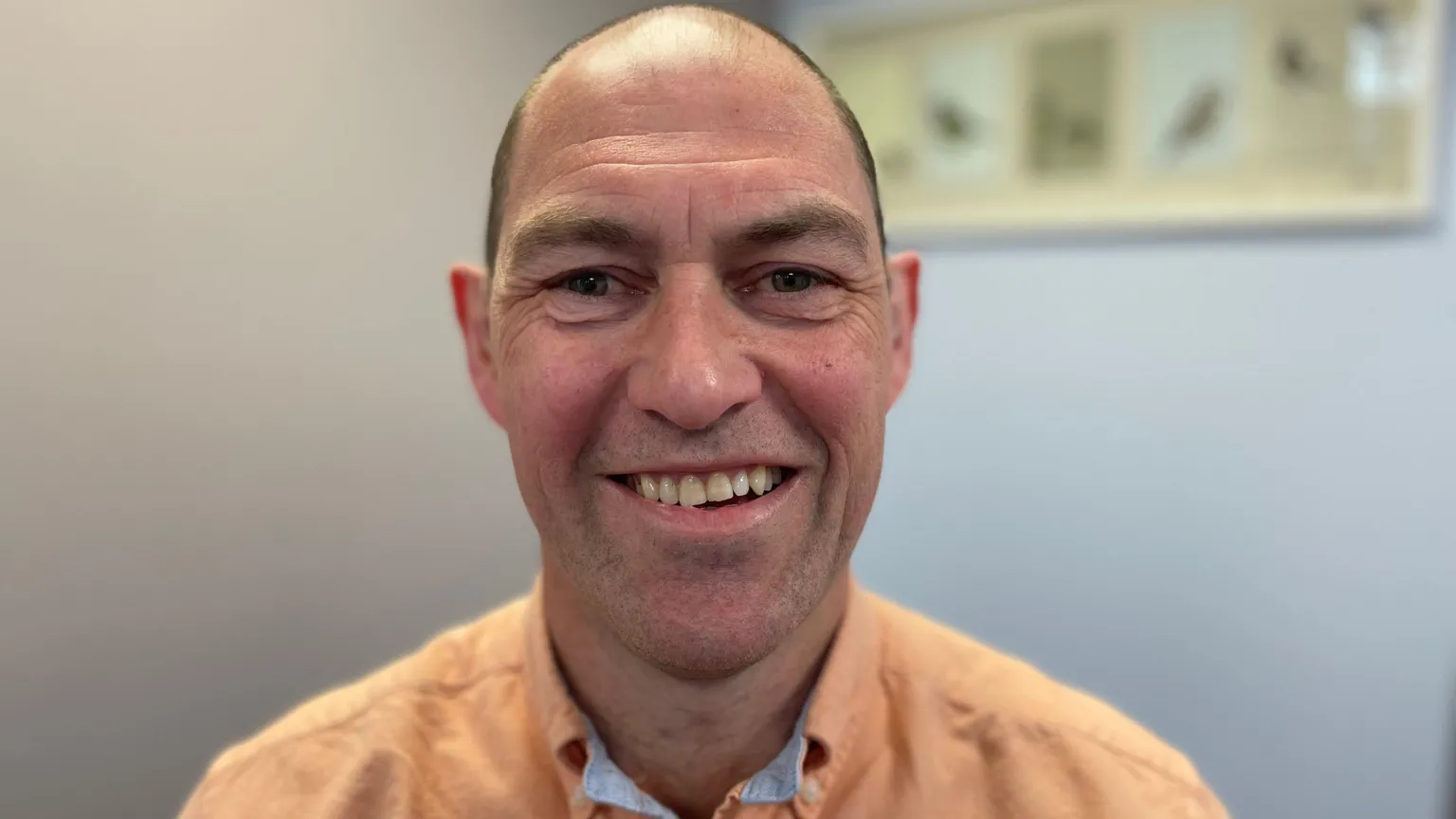 Kieran is smiling and wearing an orange shirt