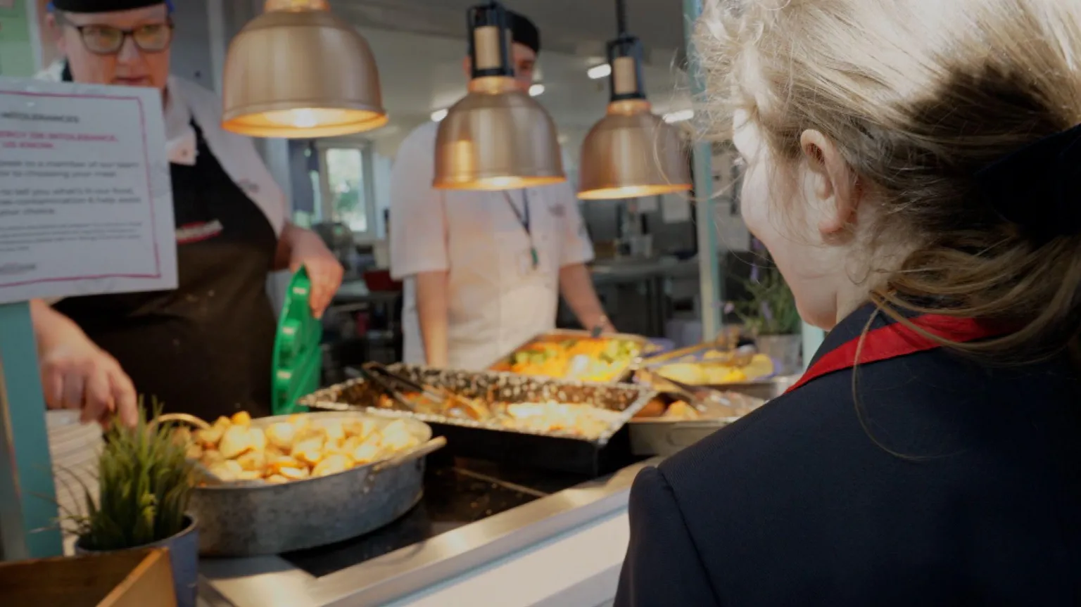 School student is being served by dinner lady in canteen.
