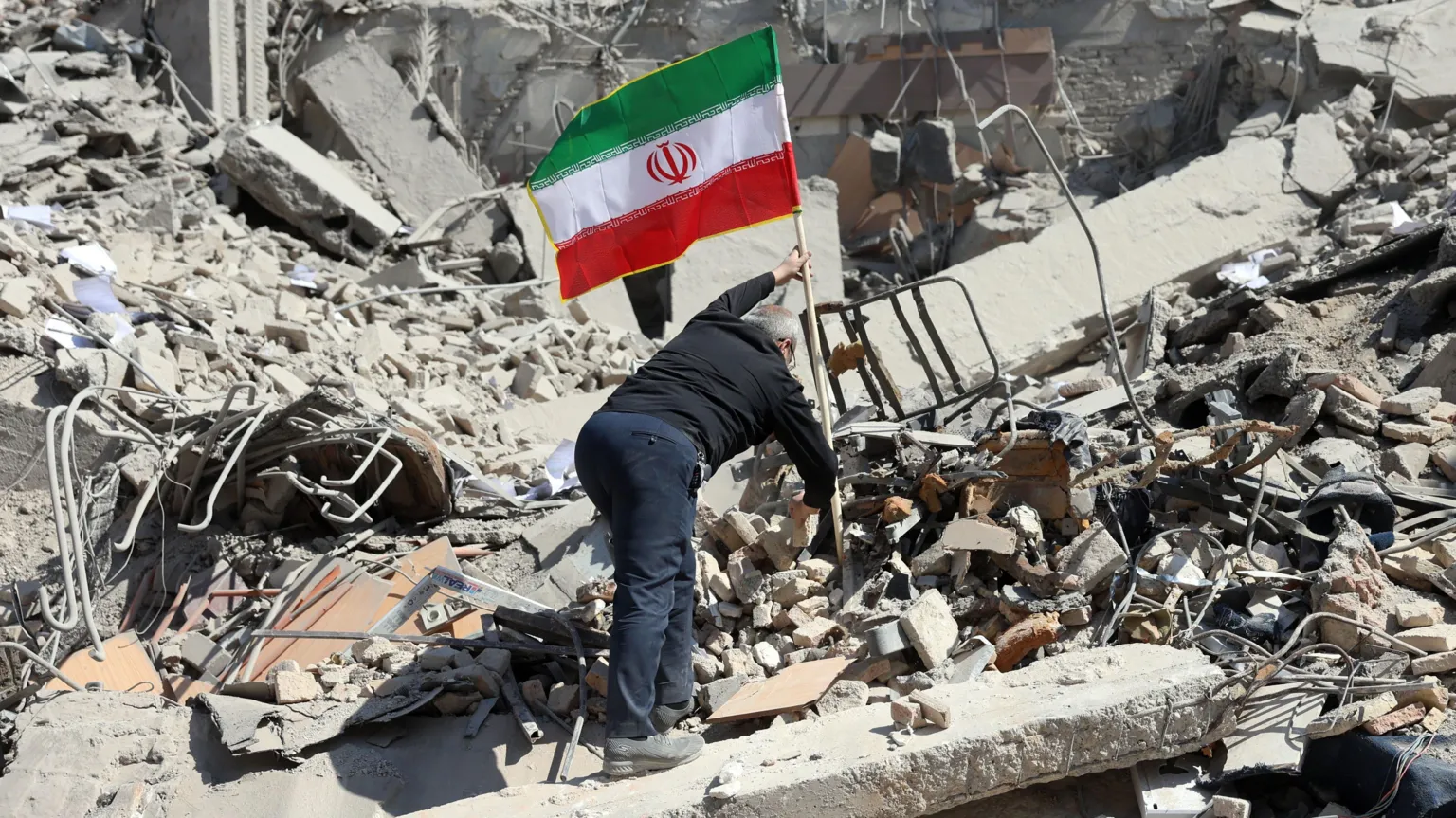 EPA A man plants the Iranian flag on a pile of rubble in Tehran.