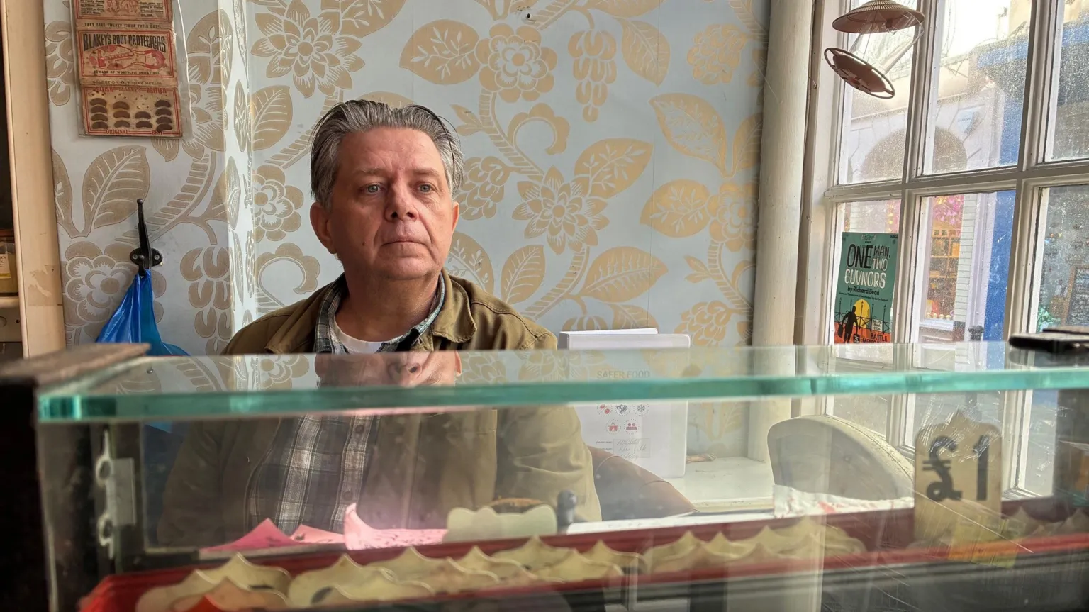 Alex White sits behind the till in his shop.