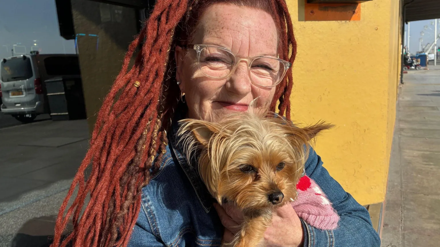 Sharona sits on a step holding her dog, Luna.