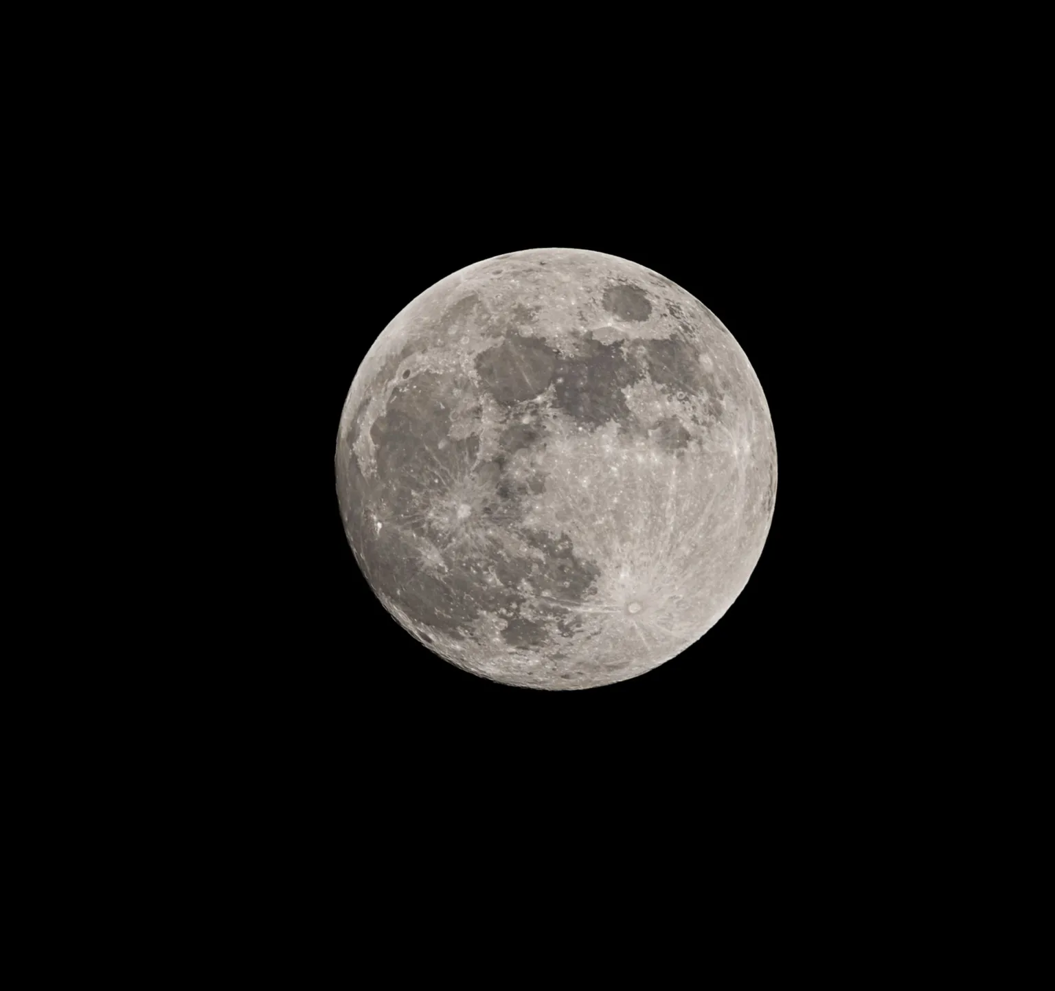 Andrew McIntosh The full Moon appears centred in the frame, with its surface features—craters and grey lunar maria—clearly visible against a stark black background.