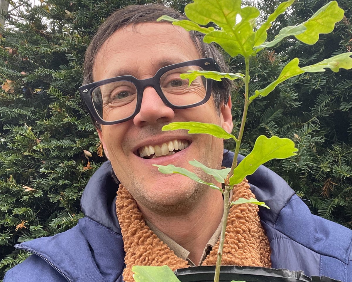 Barkham holding a young oak tree in a pot.