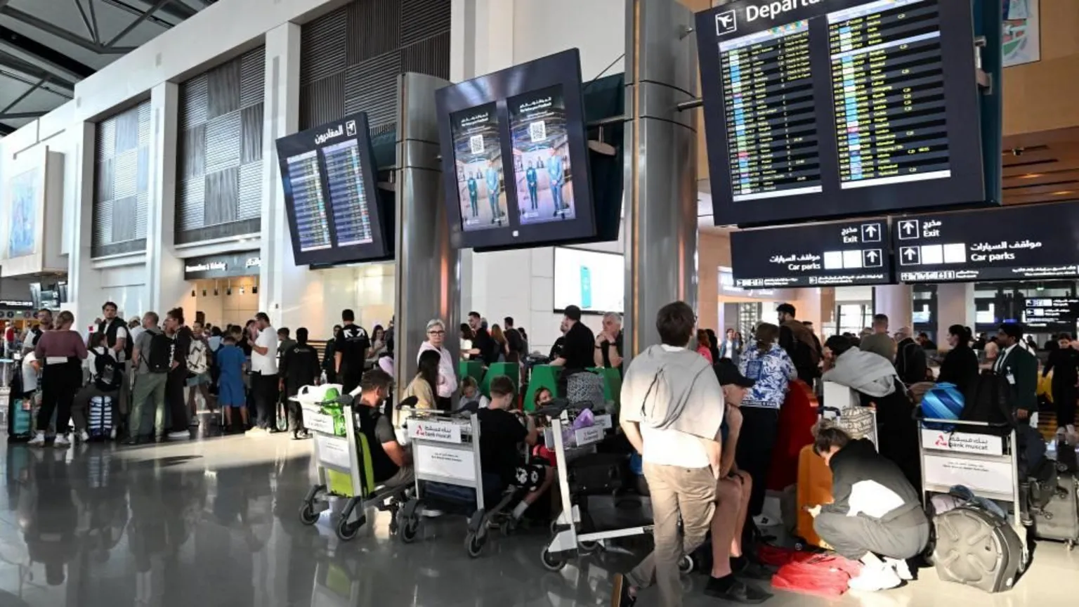  Passengers standing in front of departures boards at Muscat Airport