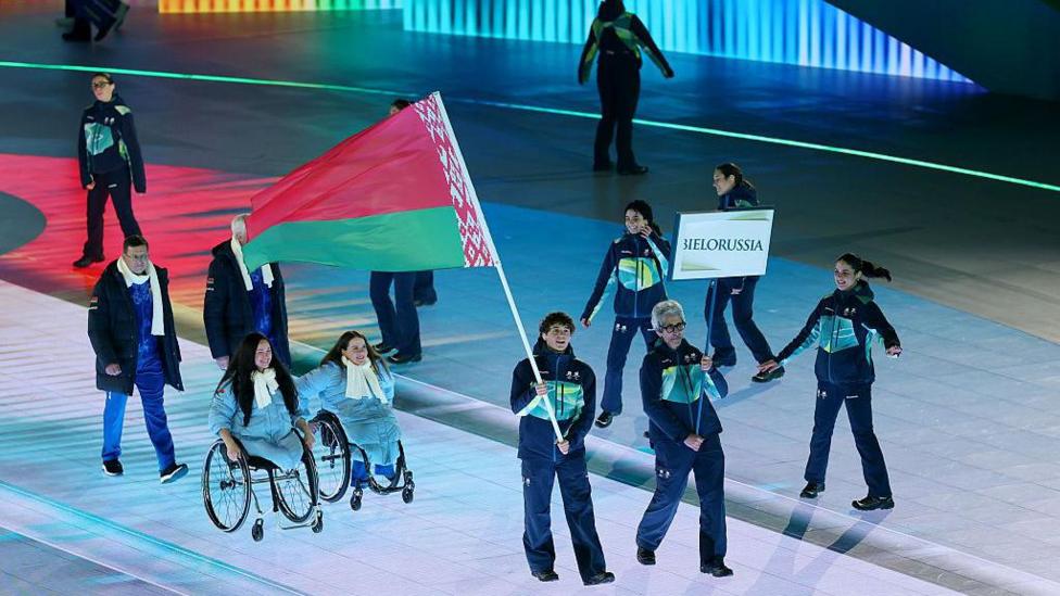 Athletes from Belarus taking part in the opening ceremony as the Belarus flag is carried by a volunteer