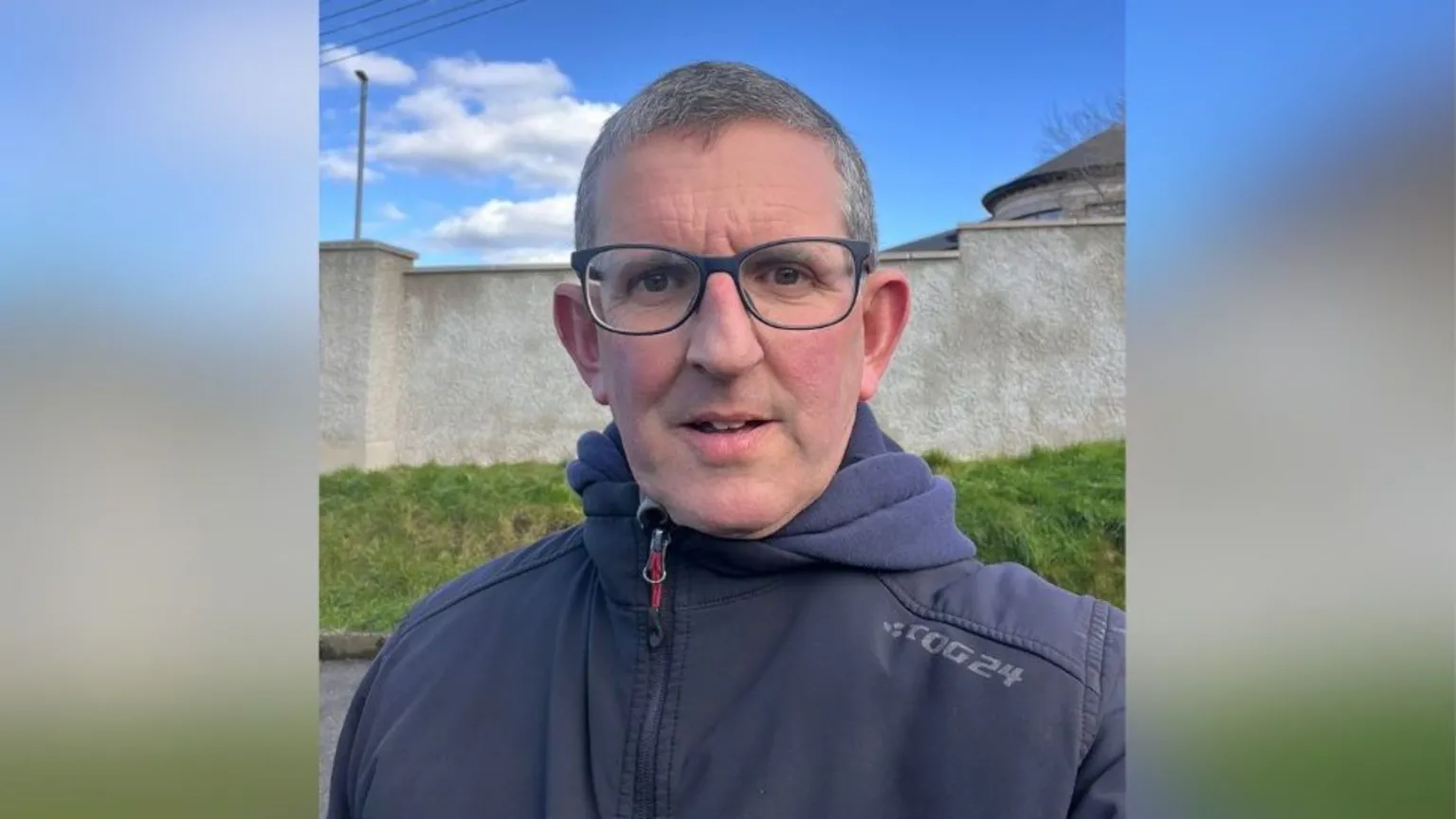 Gareth Barker Gareth Barker has short salt and pepper coloured hair and black framed glasses. He is wearing a zipped up navy coat