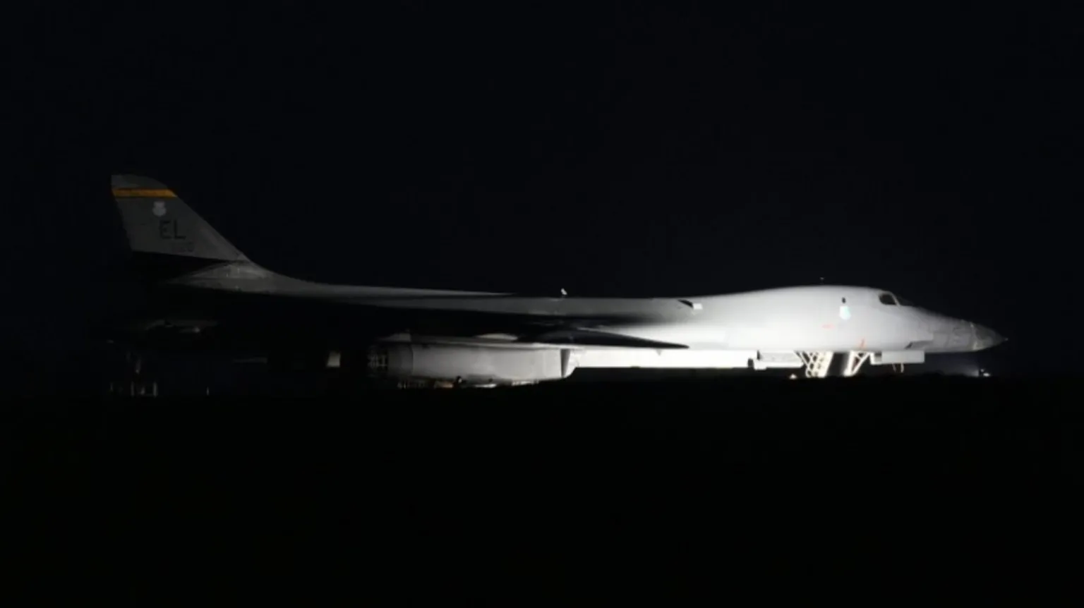 A white bomber plane is pictured flying through the dark night's sky.