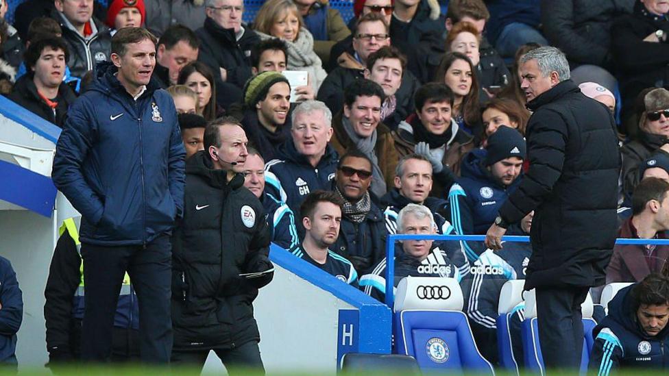 Phil Parkinson stands in the dug out at Stamford Bridge with Jose Mourinho turning to look at him 