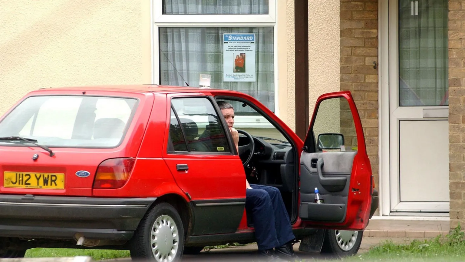  Image shows Ian Huntley biting his nails in the open driving seat of his red Ford car in 2002 while the search for the two girls was ongoing 