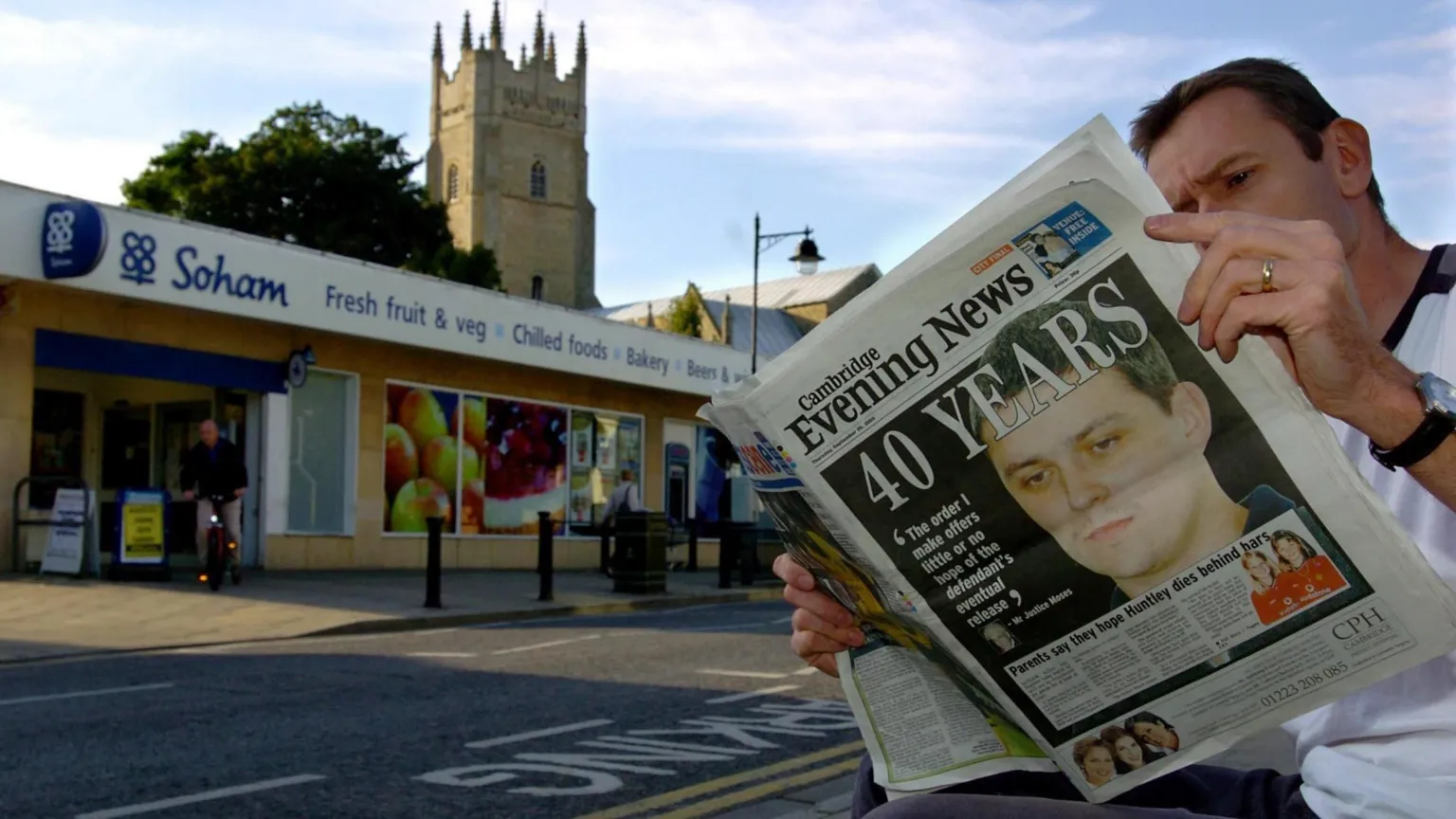  A man reading the Cambridge Evening News newspaper in front of a Co-op shop in Soham. The front page shows Ian Huntley with the headline 