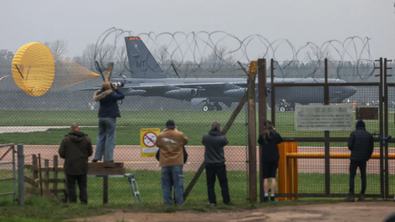  People watch from behind a barbed wire fence at the the U.S. Air Force Boeing B-52 Stratofortress bomber landing at RAF Fairford airbase, used by United States Air Force (USAF) personnel, amid the U.S.-Israeli conflict with Iran,