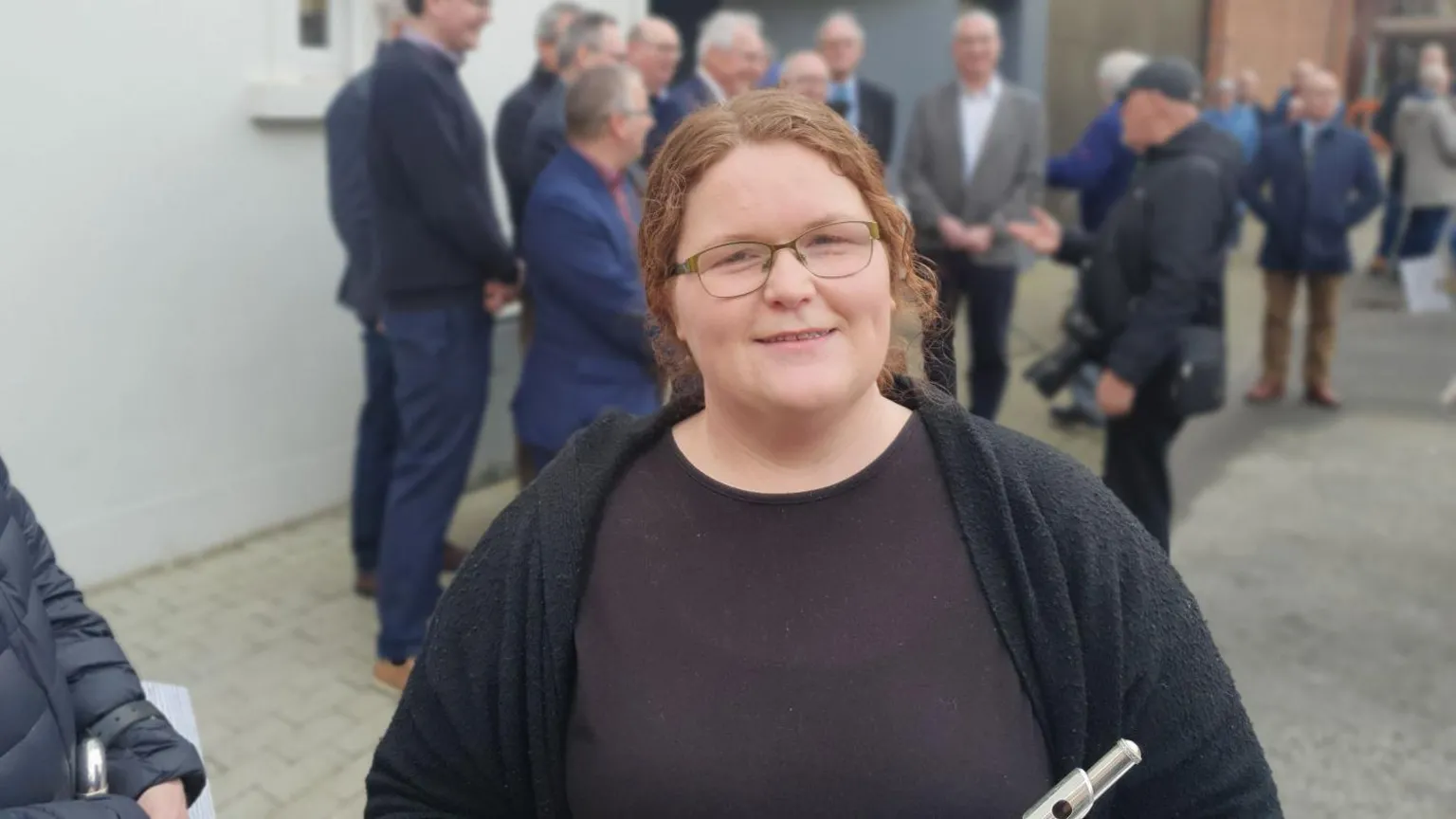 A red headed woman with glasses and a back t shirt.
