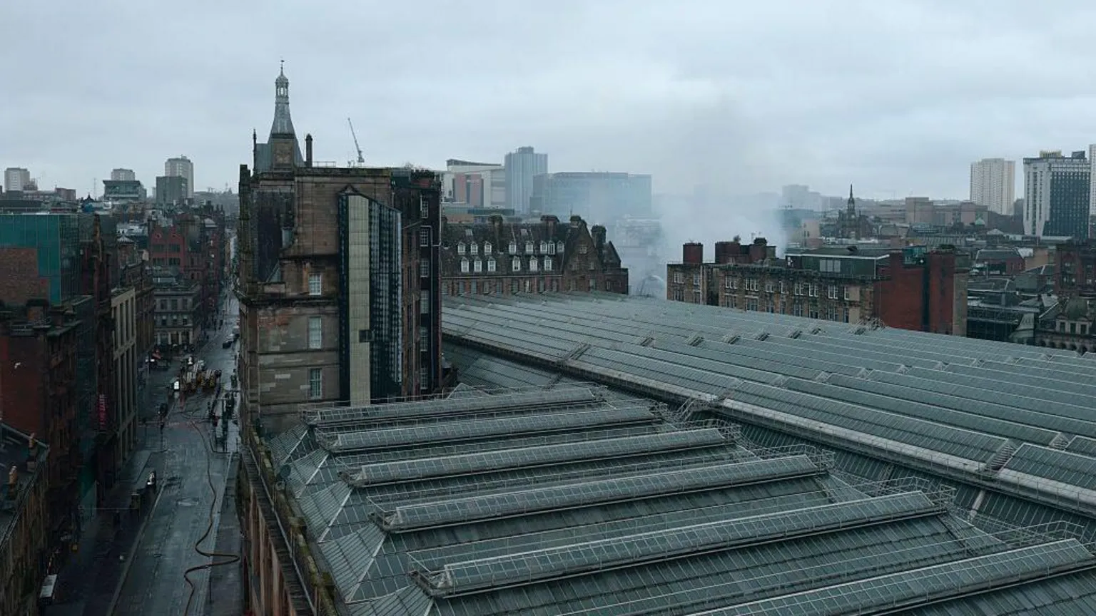  An aerial view from the south west as firefighters continue to damp down the remains of a fire in a building at the north east corner of Glasgow Central Station. The Victorian grid streets are seen around the glass roof of the railway station.