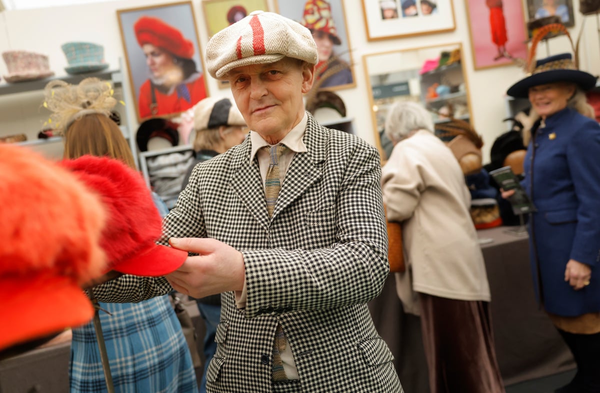 Beardsall, wearing a baker boy-style cap and houndstooth jacket, arranges some of his hats on display