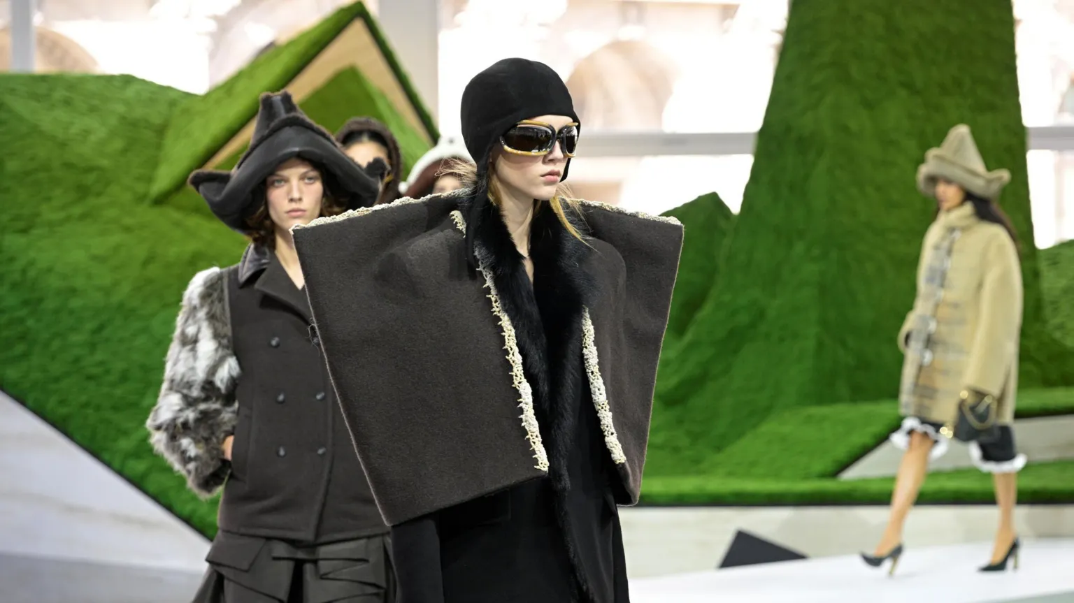  Models wearing wide-shouldered jackets and conical hats at Louis Vuitton show