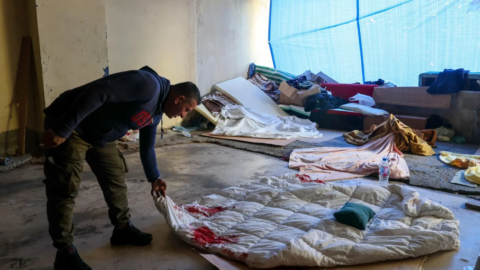 EPA A displaced Lebanese man holds a blood-stained duvet following an Israeli strike on the Ramada Plaza hotel in Beirut's Raouche district, during which his children were injured by shrapnel (8 March 2026)