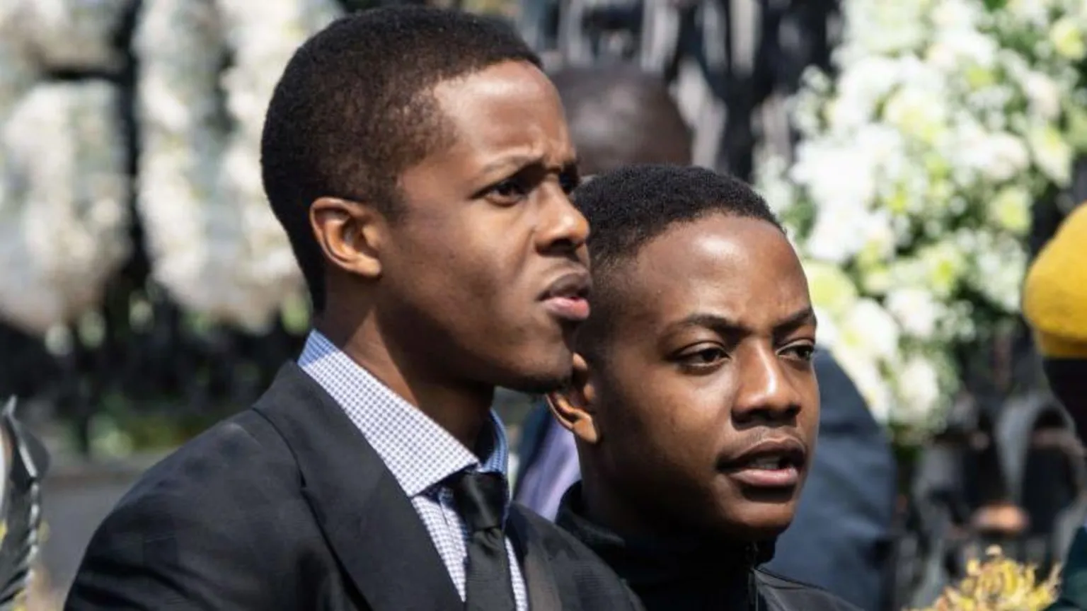 AFP via Robert Mugabe's son, Robert Jr and Bellarmine, are seen standing next to one another in black suits
