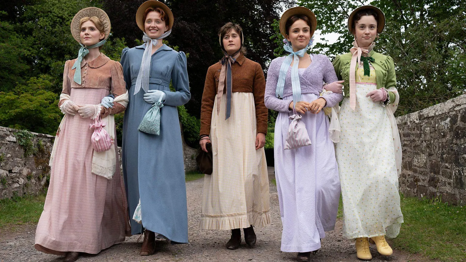BBC/Bad Wolf/James Pardon The two bennet sisters on the left and right wear colourful period costumes of dresses and cropped cardigan ( L-R- pink, blue, purple, green). Mary, in the middle, wears a more basic white dress, a brown cropped cardigan and a beige head scared.