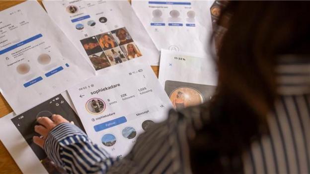 Llun a dynnwyd o gefn Sasha-Jay yn ddangos hi'n edrych ar y brintiau A4.