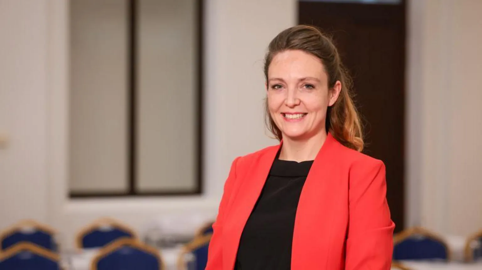 Department of Education Lucy Crehan in black top and red jacket