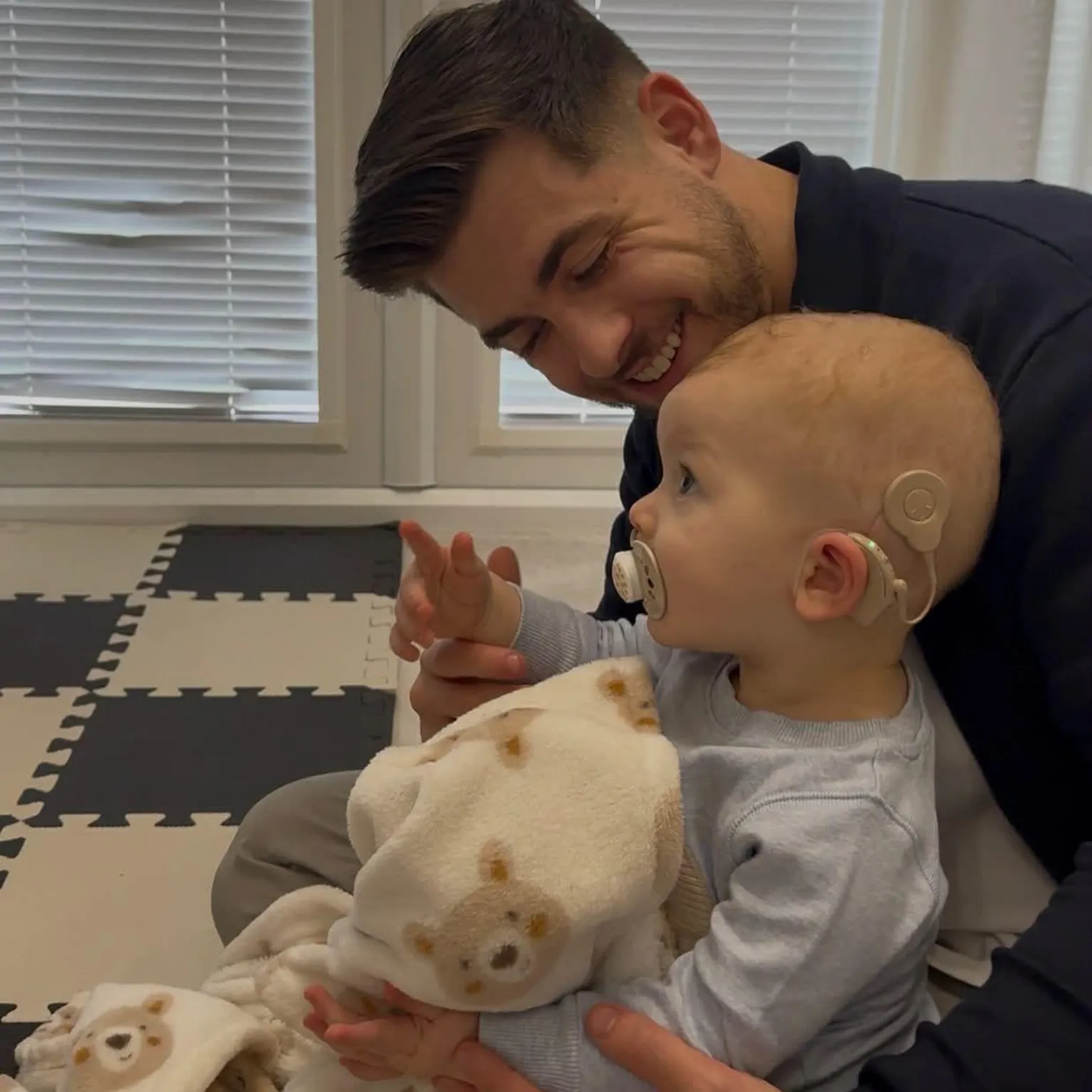 Morgan Deakin A man holding a baby wearing blue and holding a blanket with teddy bears on it