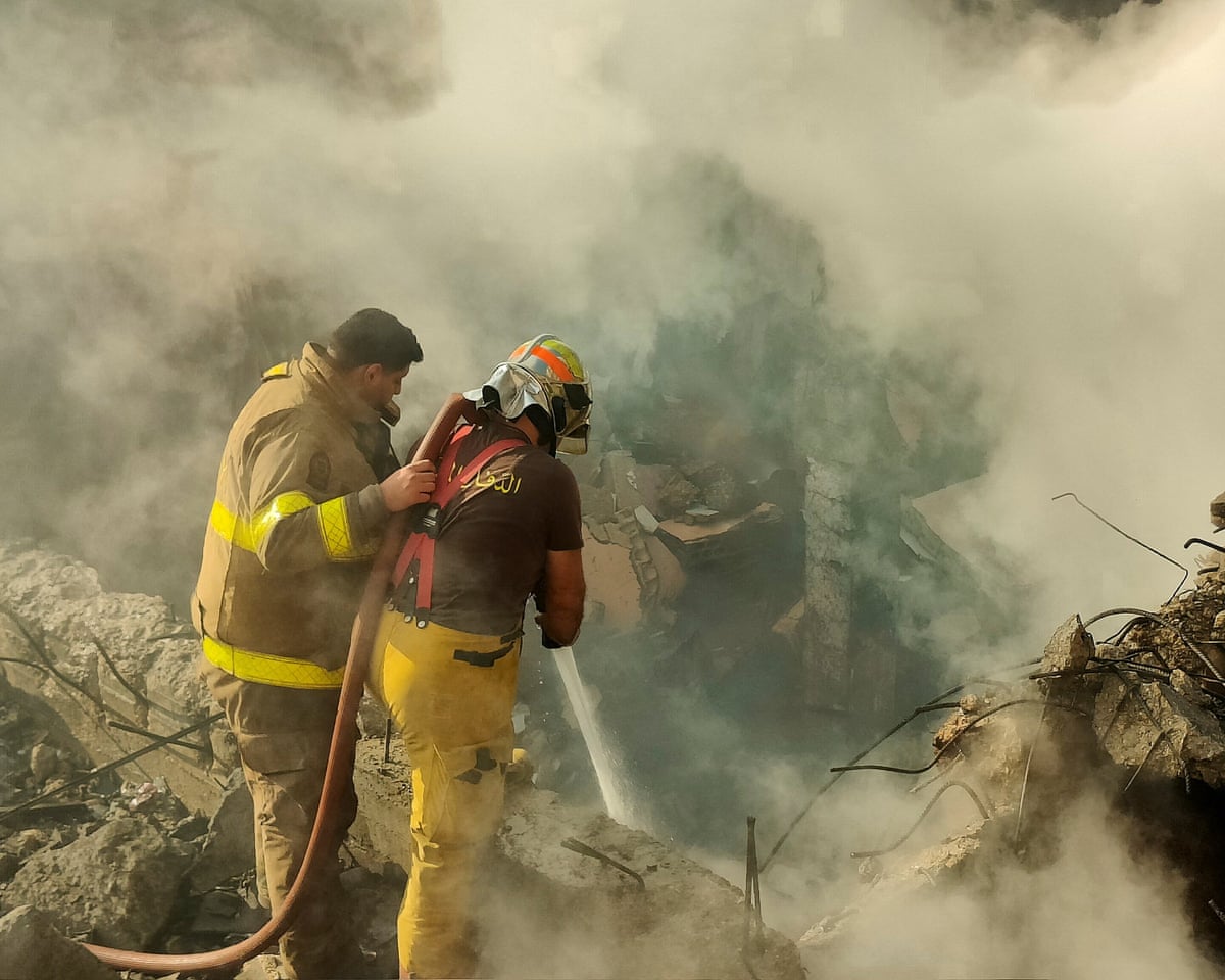 Smoke rises as Lebanese civil defence personnel work to extinguish a fire in a building destroyed after an strike in Beirut’s southern suburbs amid an escalation between Israel and Hezbollah