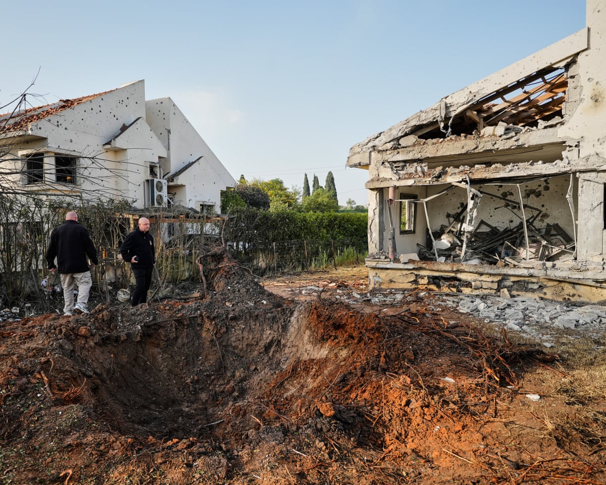 People inspect homes in Haniel, central Israel, damaged by a projectile launched from Lebanon