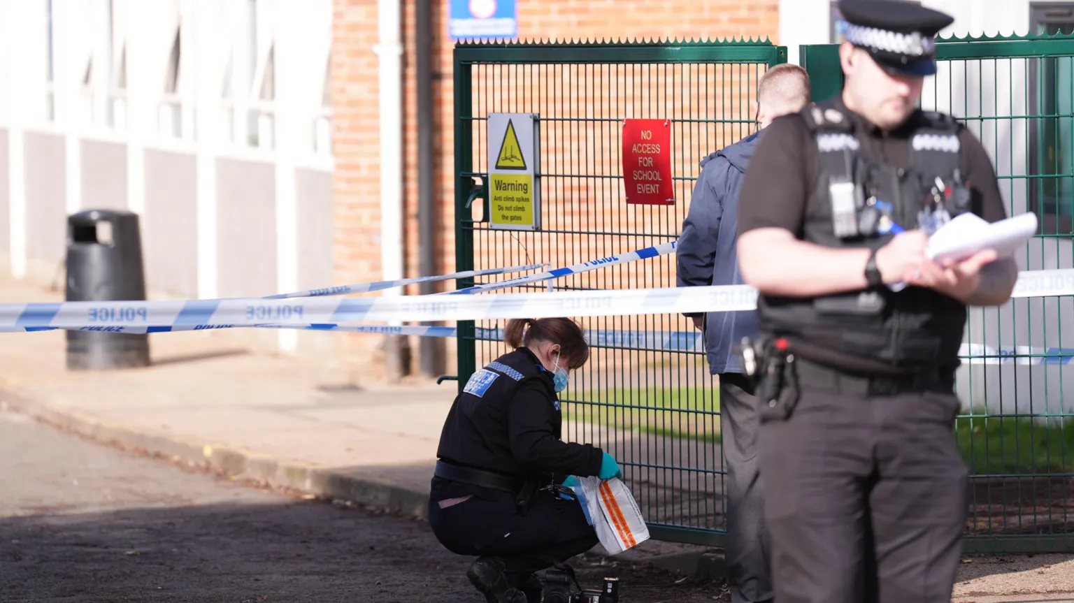 PA A police cordon is pictured at a school. Three police officers can be seen looking at paperwork