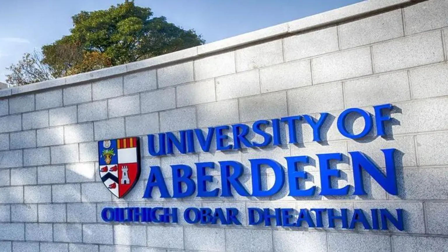 University of Aberdeen Bold blue lettering which says 'University of Aberdeen' on a wall.