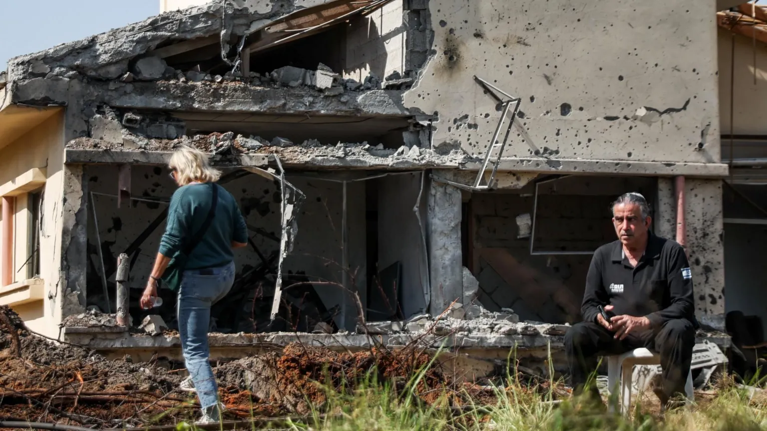  People outside a damaged building in central Israel that was hit by a projectile launched from Lebanon by Hezbollah (12 March 2026)