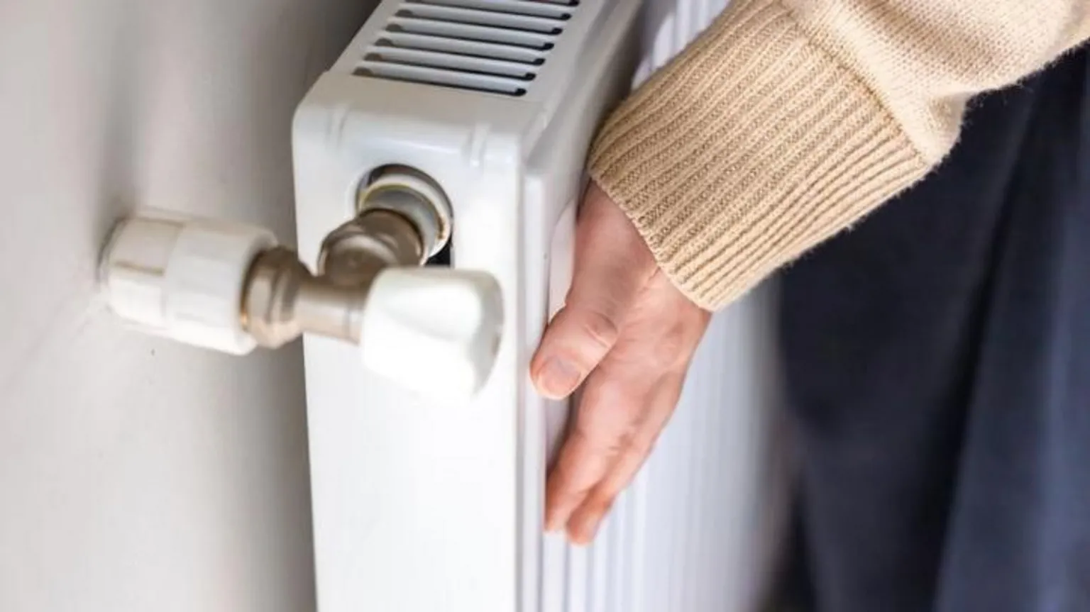 A white heater, with a hand on it. There is a control to the left.