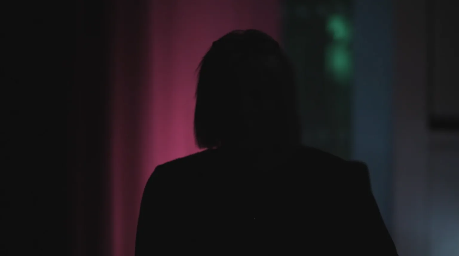 A silhouette of a woman with bobbed hair on a background of purple and blue light.