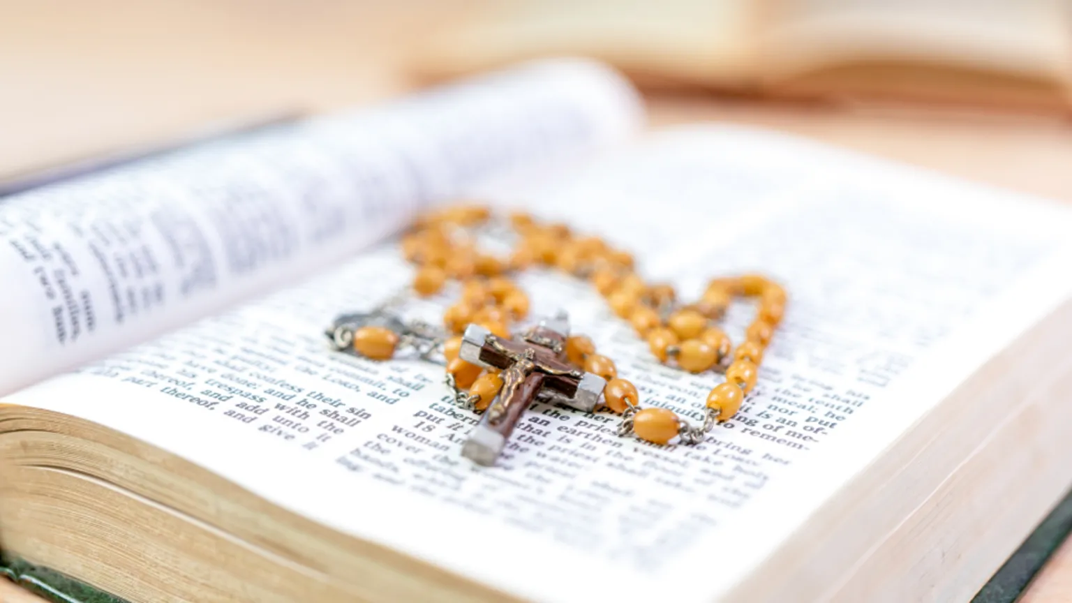  A bible, sat open with brown rosary beads on top.