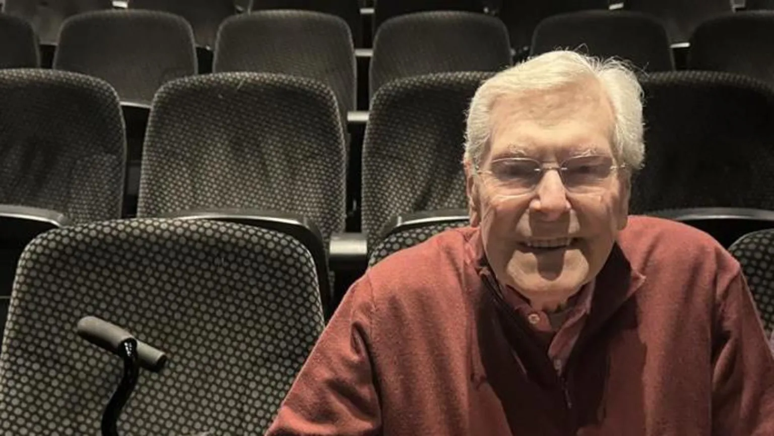 A man smiling sat in the seats of a cinema