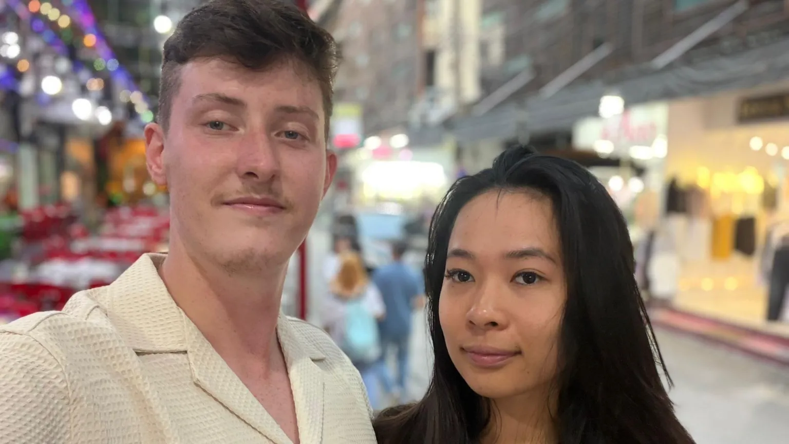 Ashley Jones and Trang Nguyen Ashley Jones wearing a pale yellow shirt taking a selfie with partner Trang Nguyen in Bangkok