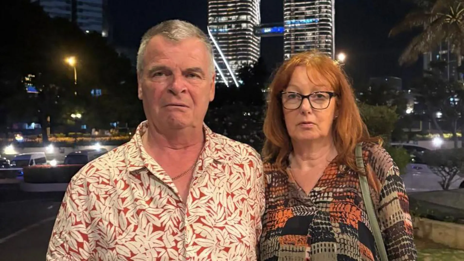 Debbie Rainbird Ardon Rainbird and wife Debbie wearing colourful and patterned holidaywear standing in Sri Lanka with tower blocks behind them