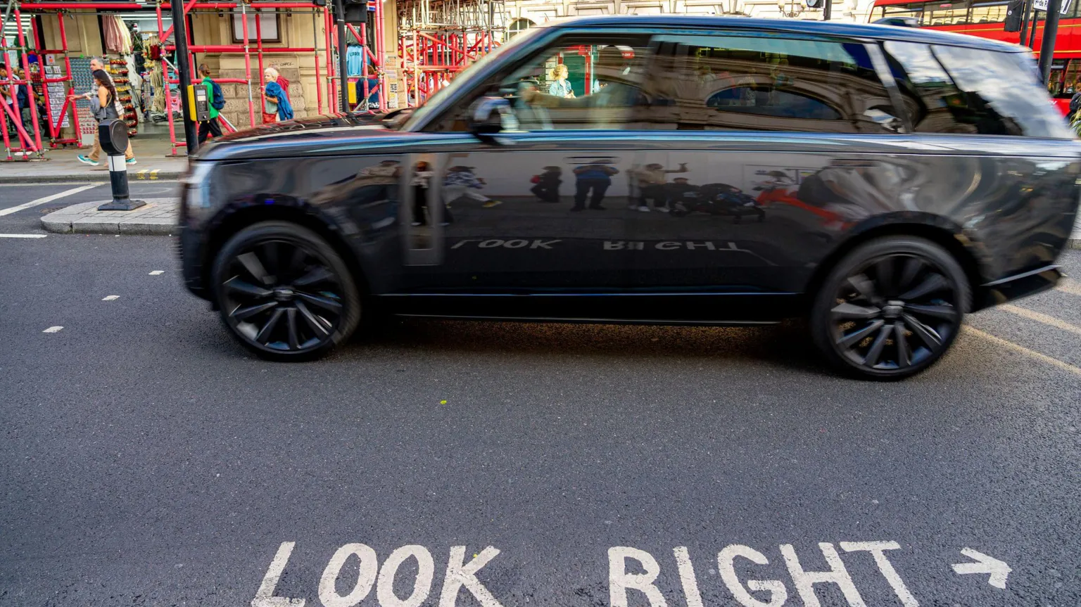  A dark grey SUV drives past some traffic lights in London