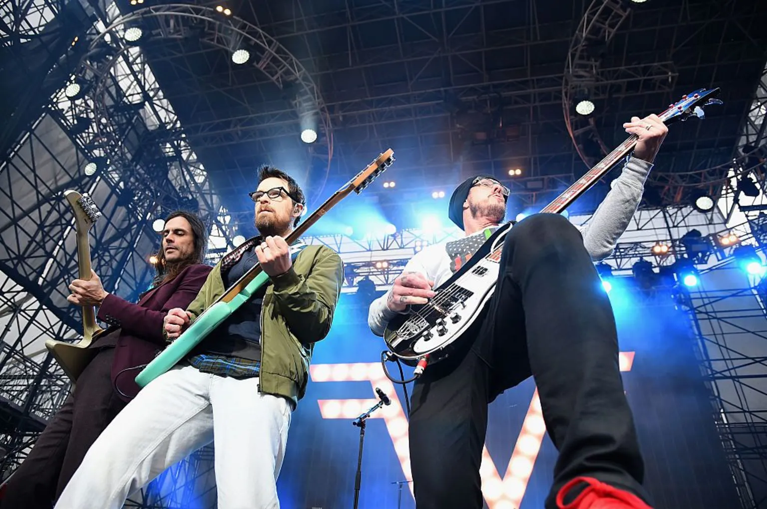 Weezer are shot from below as they perform on a vast stage surrounded by scaffolding