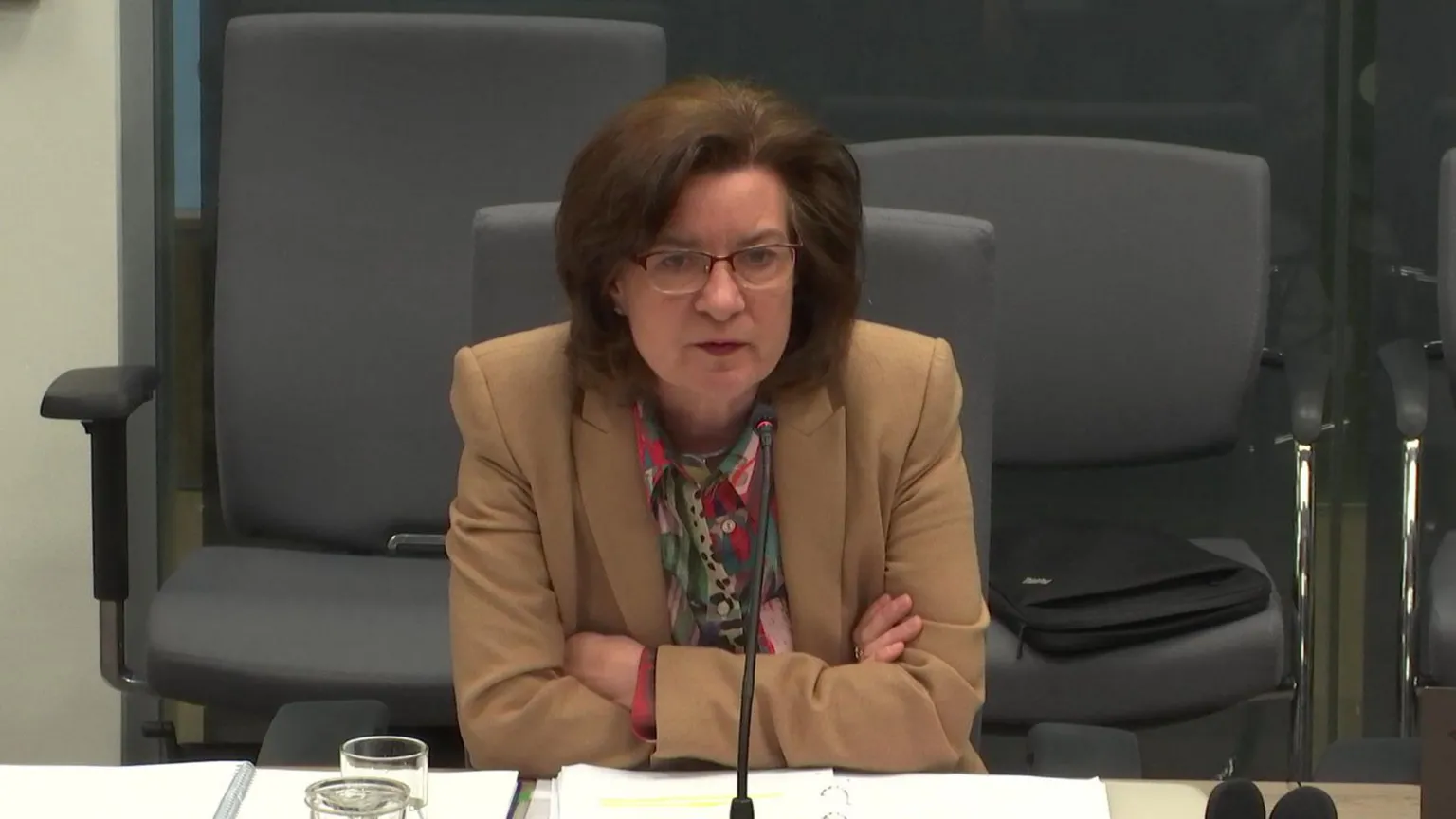 Senedd Commission Eluned Morgan being questioned in committee. She is leaning against the desk and has her arms folded.