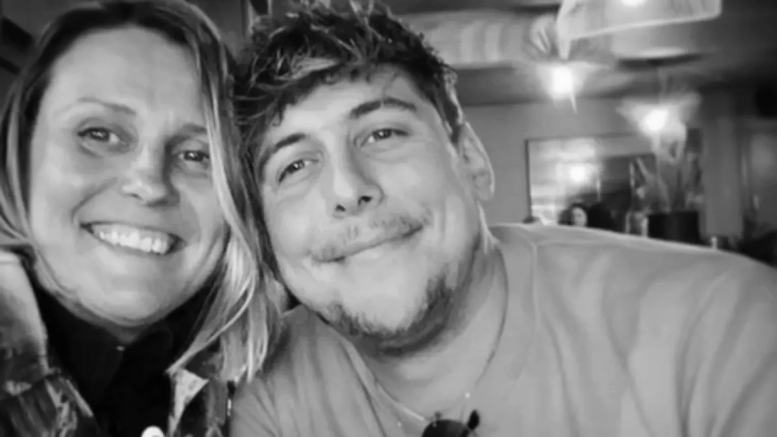 Joe Bennett A black and white photo of a woman and a man - Lindsay and her son Joe - smiling at the camera. 