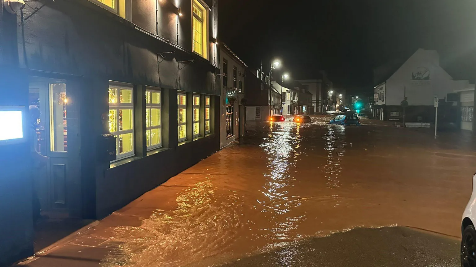 Andrea Shull Outside the restaurant in darkness. Brown water in the streets. Two cars stuck in water in the distance