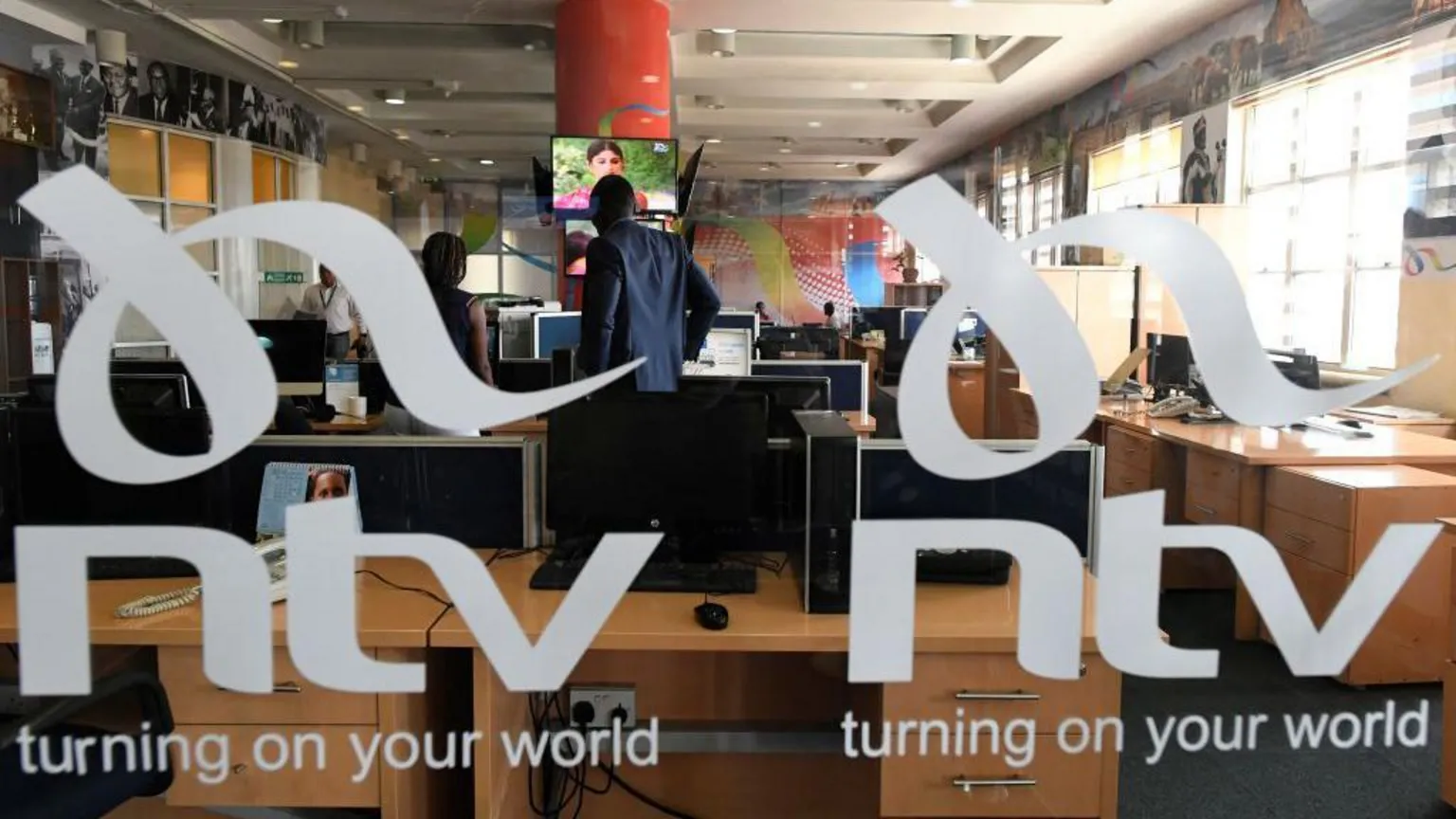 AFP via Looking through some branded glass - with the logo of NTV on it. People in a news office can be seen in the background.