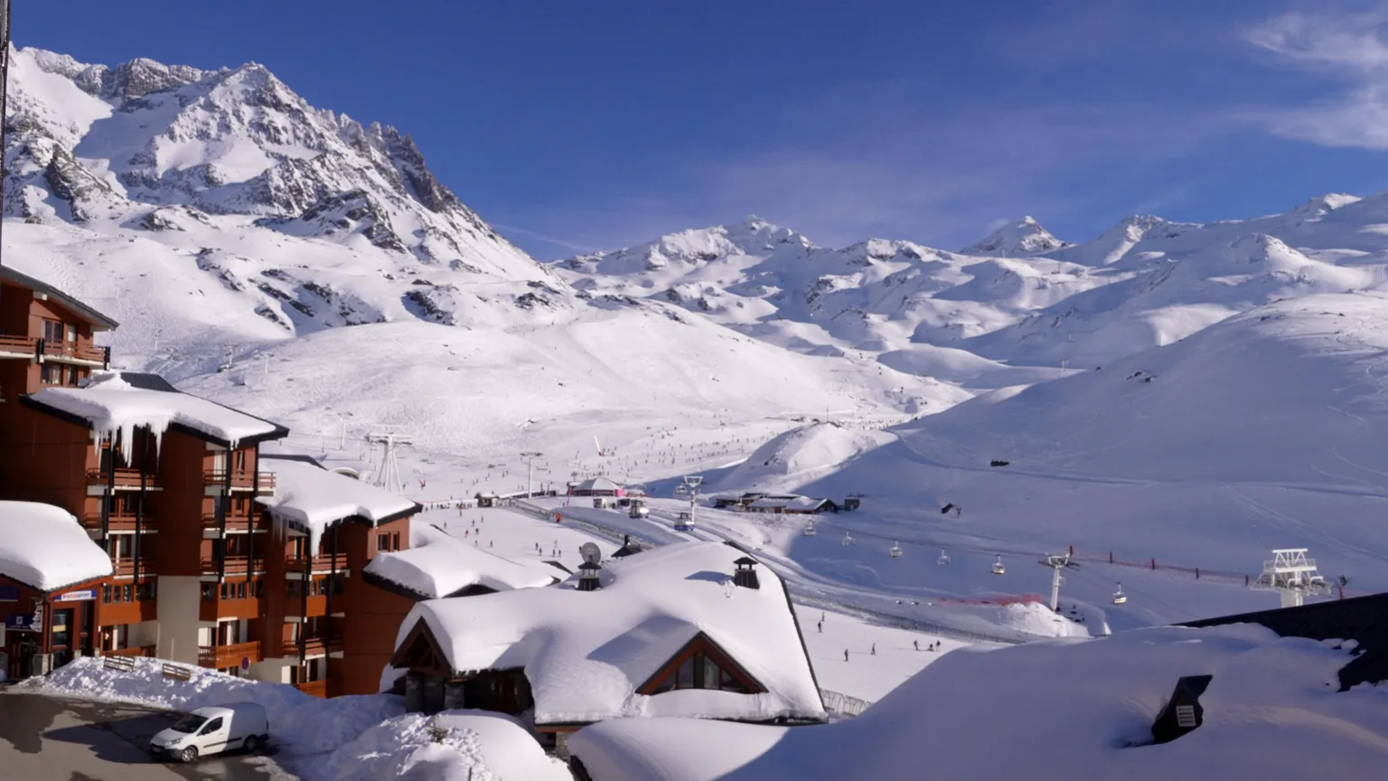 Mountains covered by snow with the buildings and ski lifts of a ski resort in the foreground